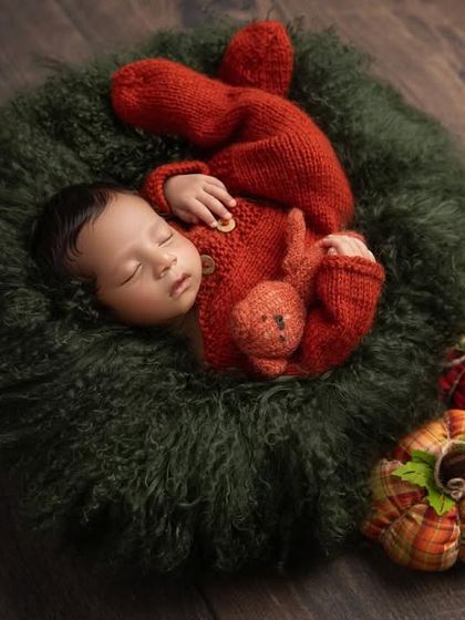 A slightly different angle of the festive wreath setup, highlighting the adorable plaid and burlap pumpkins that add a rustic, warm touch to this baby's first autumn or Christmas photoshoot.