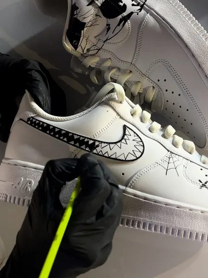 Here's a close-up of our live art process. An artist meticulously hand-paints a sharp, graphic design onto a fresh Nike Air Force 1 during an event, showing the skill and precision we bring on-site.