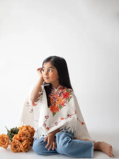 A thoughtful, candid moment captured during the denim-themed shoot. The embroidered poncho adds a lovely, unique touch.