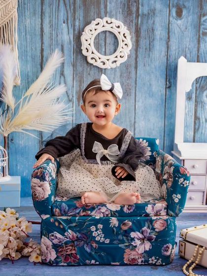 This little girl looks so sweet and content in this floral armchair, a perfect prop for a classic toddler portrait.