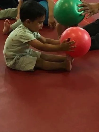 A close-up of a toddler engaged in a ball exercise, focusing on his movements. This simple activity helps with motor control and concentration.