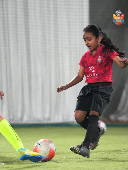 A young girl practices dribbling, showing great focus and determination.
