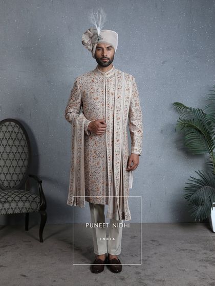An ode to modern royalty, this coffee-beige sherwani is adorned with 3D floral embellishments and intricate beadwork. It is a portrait of heritage reimagined for the urban gentleman.