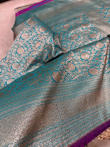 The pallu of the teal and magenta Banarasi silk saree, featuring a beautiful floral jaal weave in antique gold zari.