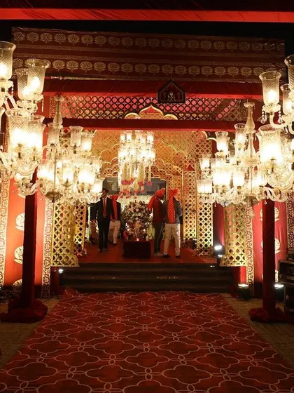 A grand entrance for a royal-themed wedding, featuring stunning crystal chandeliers and rich red carpets to welcome guests into the celebration space.