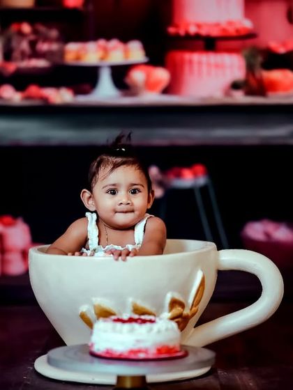 A cup of cuteness. Our oversized teacup prop is a unique and playful element, shown here in our sweet shop setup, which features a background filled with cakes and pastries.
