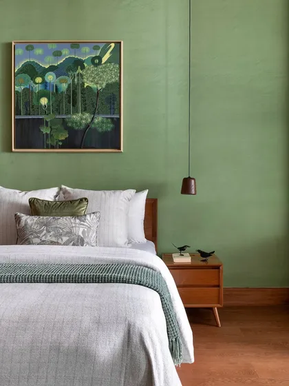 This bedroom was envisioned as a personal gallery for a nature photographer. The green lime-washed walls provide a vibrant backdrop for displaying artwork, while the wooden furniture adds warmth and texture.