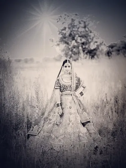 An artistic black and white bridal portrait in a field, with a sun flare effect that adds a dramatic touch.