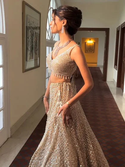 A full length shot showing how a high, voluminous bun can balance a heavily embellished lehenga. It adds height and elegance to the overall silhouette.