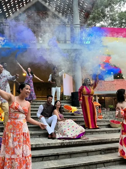 The joy of a Mehendi party is captured in this lively group shot with colorful smoke filling the air.