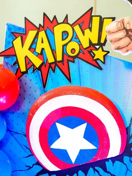Captain America's shield and a "KAPOW!" sign are part of the vibrant, comic-inspired details that decorate the party space.