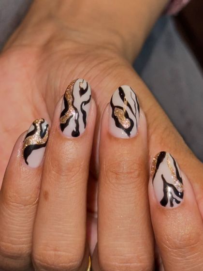 A fierce and glamorous design featuring black and gold glitter zebra stripes on a nude base.