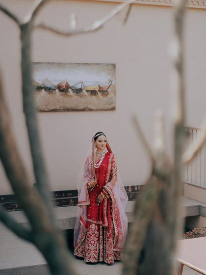 A creative bridal portrait, with the bride framed by the branches of a tree. This use of natural framing adds depth and an artistic touch to the image.