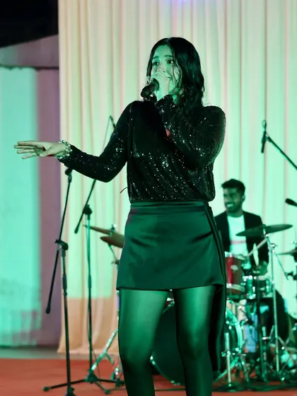 A full-length shot of me performing with the drummer in the background. Our 5-piece band setup includes vocals, guitar, bass, keyboard, and drums.