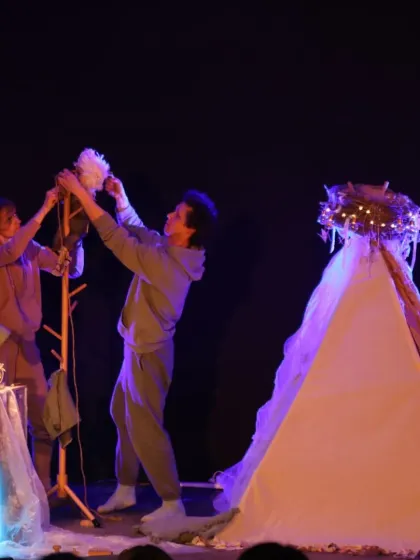The puppeteers of 'Sea of Possibilities' work together on their imaginative set, which includes tents and glowing lights, creating a dreamlike atmosphere.