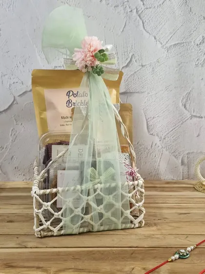 A charming white woven basket filled with our handmade snacks like Potato Brickles, making for a lovely and rustic Rakhi gift.