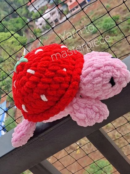 A plush strawberry turtle on a balcony railing.