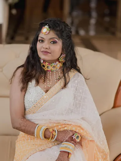 A royal glam Haldi look. The bride looks stunning in her white and yellow saree, with makeup that is both elegant and festive.