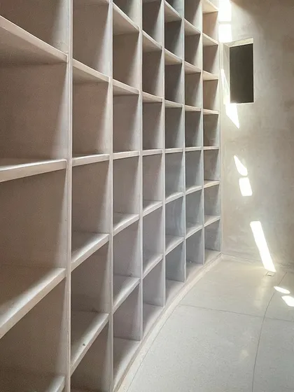 A grid of storage niches follows the curve of a wall in the House of Galleries. The repetition of the simple square form creates a powerful visual rhythm, animated by the light from a nearby skylight.