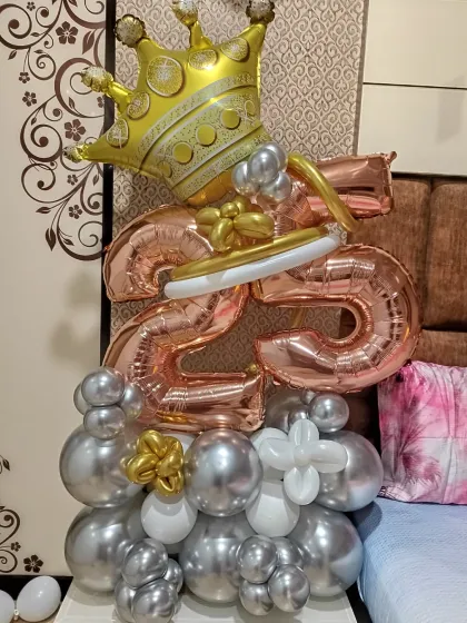 A stylish balloon bouquet for an anniversary. This arrangement features rose gold number "25" foils, a crown, and a base of silver and gold chrome balloons.