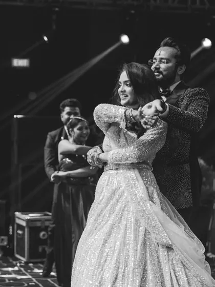 A black and white photo capturing an intimate moment during a couple's dance, with snow spray adding to the magical atmosphere.