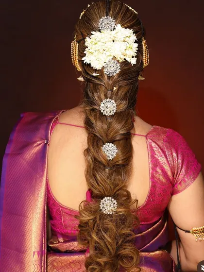 A stunning and modern take on a bridal braid. This hairstyle features sections embellished with sparkling crystal accessories and fresh flowers at the crown.