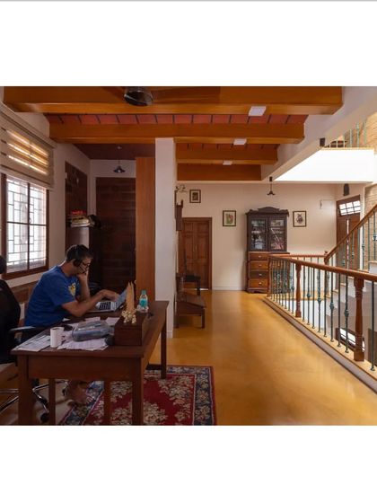 A functional home office space is seamlessly integrated into the open corridor, featuring a jack arch roof and warm earth tones that create a productive yet peaceful atmosphere.