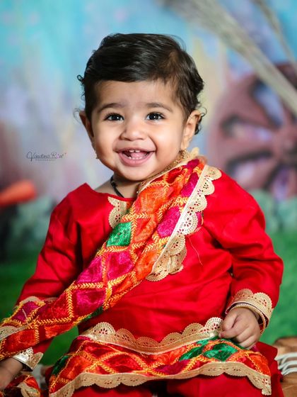A big, toothy smile from this little one during the Lohri/Pongal festive session. The colorful outfit and background create a joyful and celebratory image.