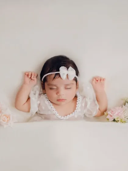 A duplicate of image 36, this image captures the serene beauty of a newborn baby girl surrounded by soft roses. The focus is entirely on her peaceful sleep.