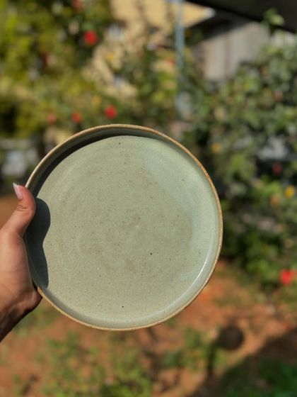 A Chun plate held up in the natural light, showcasing the soft, speckled texture of the glaze. We are currently taking preorders for these.