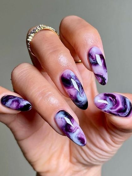 A mystical and moody design, these nails feature a purple and black marble effect that looks like a swirling galaxy. It's a captivating and unique look for anyone who loves darker, more dramatic nail art.