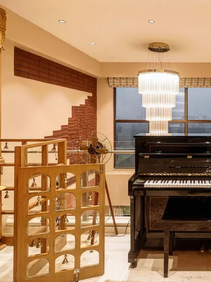 A view of a pooja unit next to a piano, showing how spiritual spaces can be integrated into modern living areas.