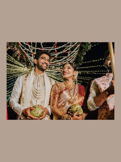 The couple sharing a smile during a traditional ritual, surrounded by the warm glow of festive lights.