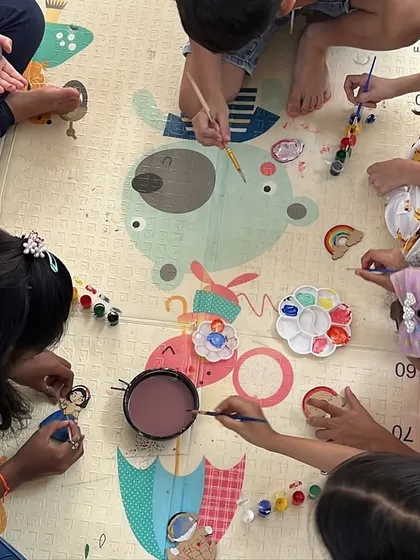 Here is a bird's-eye view of a typical day at the club. Kids gathered on the floor, sharing paints and ideas, completely lost in their creative world. We foster a collaborative and comfortable environment where friendships blossom right alongside artistic skills.