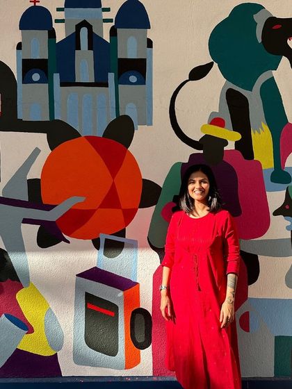 The artist in front of her mural for the Wall Art Festival, a piece inspired by the elements of France and India.