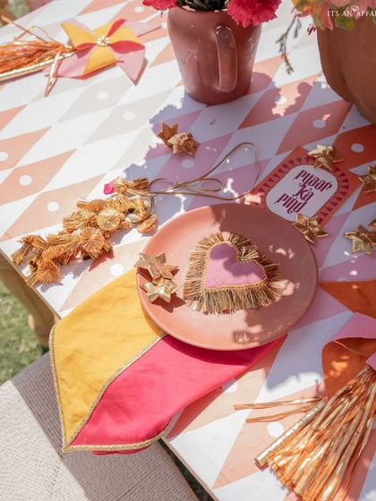 A playful table setting with a heart-shaped detail, custom 'Pyaar ka Pind' stationery, and colorful napkins, capturing the joyful spirit of the Haldi event.