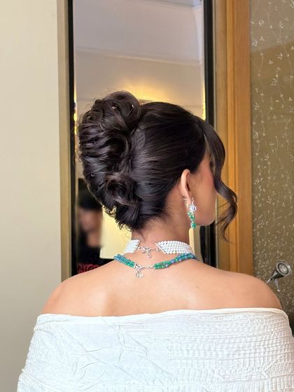 A side profile of the elegant updo, highlighting the smooth finish and the carefully placed wavy tendrils that frame the face. This ensures the style is flattering from the front as well as the back.