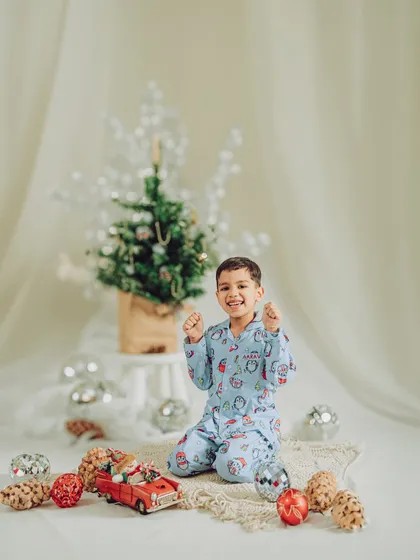 This little boy is full of excitement in his Christmas pajamas. Our holiday sets include festive props like mini trees, ornaments, and toy cars to create a playful scene.