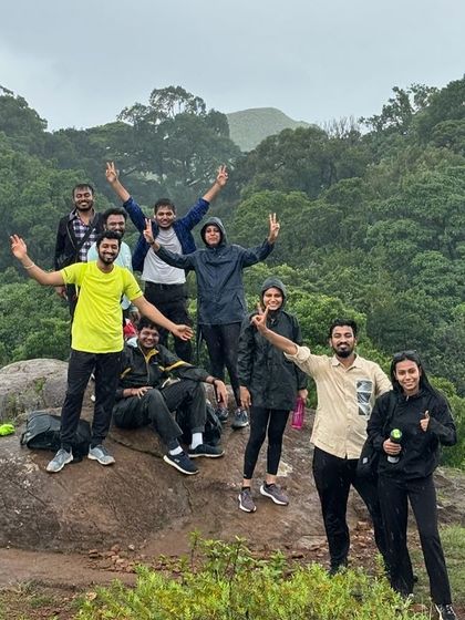 Trekkers posing on a rock amidst the lush green forest during the Bandaje trek.