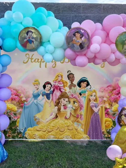 A close-up of a Disney Princess themed birthday backdrop. The colorful balloon arch includes special balloons with pictures of the princesses inside.