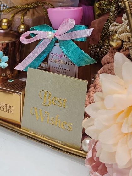 A close-up of the wedding hamper's details, including a 'Best Wishes' card, Ferrero Rocher chocolates, and a 'Gingham Gorgeous' body mist.