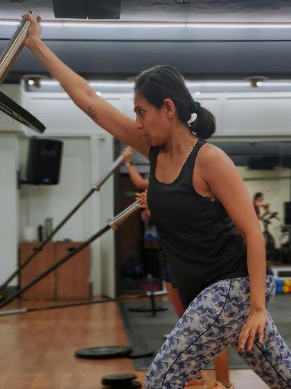 The single-arm landmine press is a great exercise for building unilateral shoulder strength and stability. Here, a member shows intense focus during the workout.