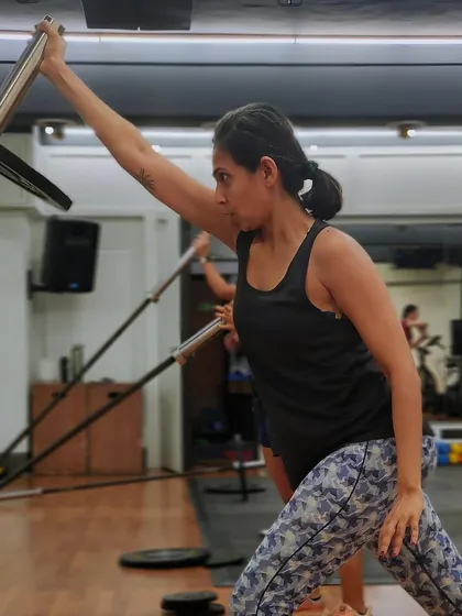 The single-arm landmine press is a great exercise for building unilateral shoulder strength and stability. Here, a member shows intense focus during the workout.