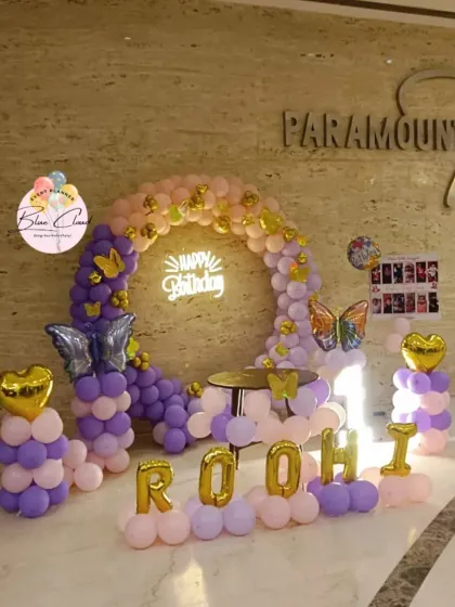 A butterfly-themed balloon ring in purple and pink, set up in a hotel lobby for a birthday party.