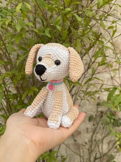 A slightly different angle of the sitting amigurumi dog, showing its friendly face and floppy ears. Each one is handmade with love in my studio.