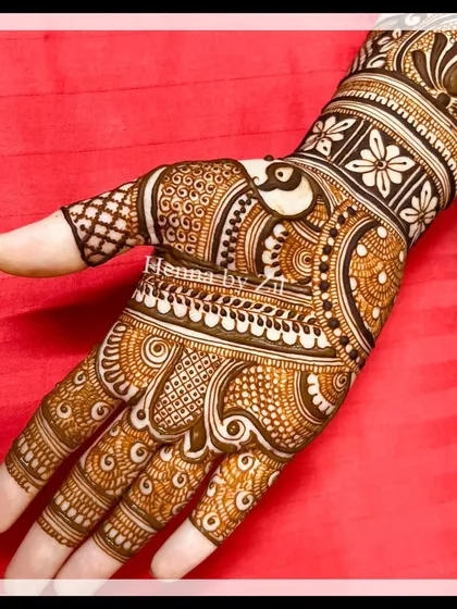 A close-up of a single hand, showing the intricate details of a traditional peacock and floral design.