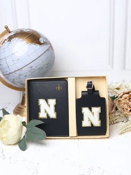 Our personalized passport cover and luggage tag set in black, displayed in its gift box. The matching chenille "N" patches make it a sleek and coordinated travel duo.