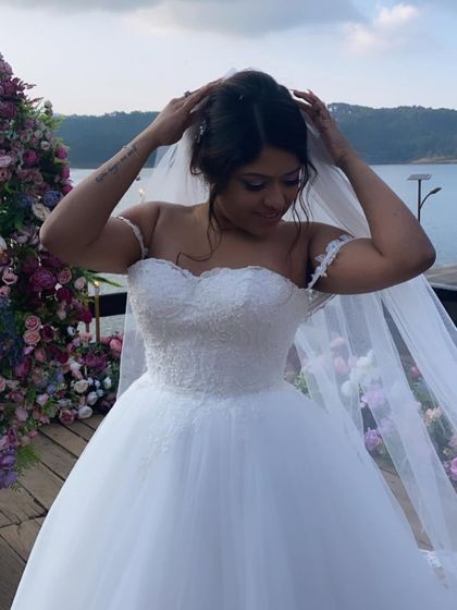 A beautiful moment of a bride adjusting her veil over a soft, romantic updo, perfect for a lakeside wedding.