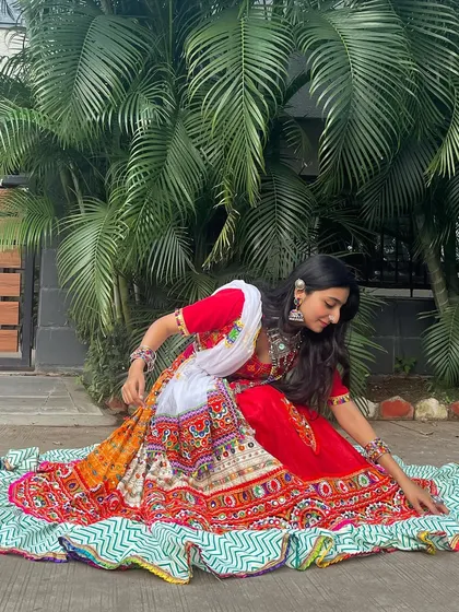 A graceful pose in a red and white lehenga with a multi-colored border. The skirt has a beautiful zig-zag pattern on the bottom layer.