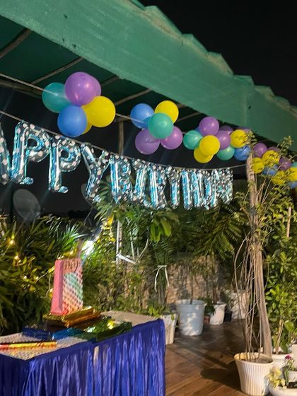 A simple yet beautiful rooftop birthday decoration. The setup includes a 'Happy Birthday' foil balloon banner and colorful balloon bunches to create a festive mood.